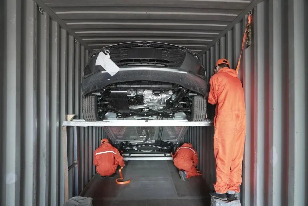 Workers lashing a vehicle inside a shipping container